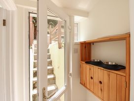 An entrance with a door and wooden shelf holding bowls at Home in Salcombe