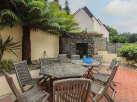A garden with a wooden table and chairs at Home in Salcombe