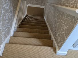 A staircase with carpet and wallpaper at Mill Stream Cottage in Lower Slaughter near Bourton-On-The-Water