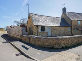 A cottage with a stone wall and a street sign at Swalbrook Place in Kingham