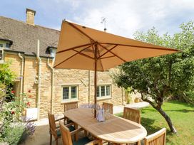 A garden with a wooden table and umbrella at Wyncliffe in Chipping Campden