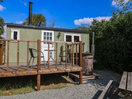 A hut with a wooden deck and hot tub at Aston - Shepherd Hut Aston On Clun