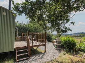 An outdoor area with wood deck, hot tub, and bench at Aston - Shepherd Hut Aston On Clun