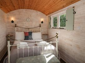 A bedroom with a bed and windows at Aston - Shepherd Hut in Aston On Clun
