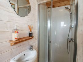 A bathroom with a shower and a small sink at Aston - Shepherd Hut Aston On Clun