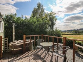 An outdoor area with a hot tub and seating at Aston - Shepherd Hut Aston On Clun