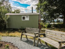 A shepherd hut with wooden benches in front at Aston - Shepherd Hut Aston On Clun