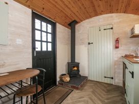 A kitchen with a fireplace and table at Aston - Shepherd Hut Aston On Clun