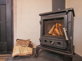 A wood stove with firewood in a living room at Aston - Shepherd Hut Aston On Clun