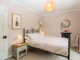 A bedroom with striped bedding and artwork at Maenllwyd Borth-Y-Gest near Porthmadog