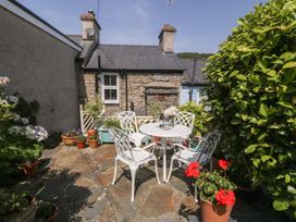 A garden with a table and chairs surrounded by flower pots at Maenllwyd in Borth-Y-Gest near Porthmadog