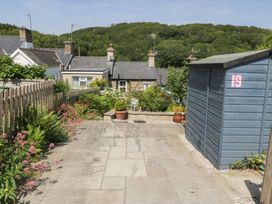 A garden with a stone patio and a shed at Maenllwyd Borth-Y-Gest near Porthmadog