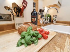 A kitchen countertop with basil, cherry tomatoes, bread, wine bottle, and glass at Charlotte House Whitby