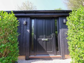 A black front door with side windows between two green bushes outside at The Haven in Cloughton near Burniston