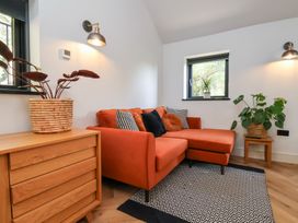 A seating area with an orange sofa and patterned cushions near wooden furniture and plants at The Haven in Cloughton near Burniston
