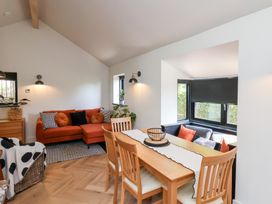 A dining area with a wooden table and chairs next to a living room with an orange sofa and a window seating area at The Haven in Cloughton near Burniston