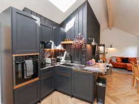 A kitchen with dark cabinets and marble countertops next to a living area with an orange sofa at The Haven in Cloughton near Burniston