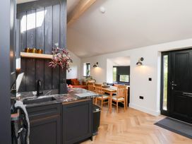 A kitchen with black cabinets and marble countertop adjacent to a dining area with wooden chairs and a black door at The Haven in Cloughton near Burniston