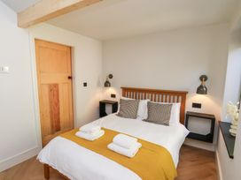 A bedroom with a wooden bed frame two pillows folded towels on a yellow runner wall lights and wooden door at The Haven in Cloughton near Burniston