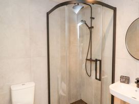A bathroom with a toilet a corner shower enclosure and a sink with a round mirror at The Haven in Cloughton near Burniston
