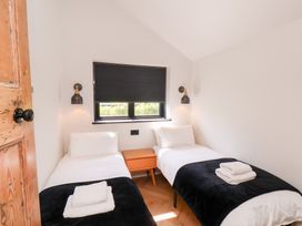 A bedroom with two single beds and a wooden nightstand beneath a window at The Haven in Cloughton near Burniston