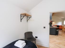 A small bedroom with a bed that has folded towels on it a chair and a wall-mounted shelf with hangers visible at The Haven in Cloughton near Burniston