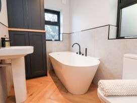 A bathroom with a freestanding bathtub a sink a toilet with a towel and a tall cabinet at The Haven in Cloughton near Burniston