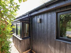 The exterior of a dark wooden building with windows and a wall-mounted light near greenery at The Haven in Cloughton near Burniston