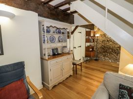 A living room with a table and shelves at Dairy Cottage in Witney