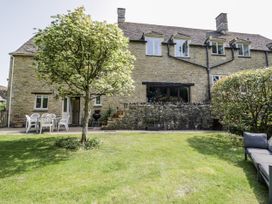 A garden with a house, chairs and a barbecue at Dairy Cottage in Witney