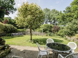 A garden with a tree, seating area and table at Dairy Cottage in Witney
