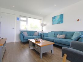 A living room with two blue sofas a coffee table and a floor lamp at 65 Channel View in Ilfracombe