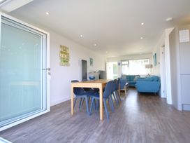 A dining area with a wooden table and blue chairs adjacent to a living room with blue sofas at 65 Channel View in Ilfracombe