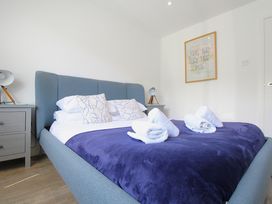 A bedroom with a bed covered with a blue blanket and white towels on it with bedside tables and lamps and a framed picture on the wall at 65 Channel View in Ilfracombe