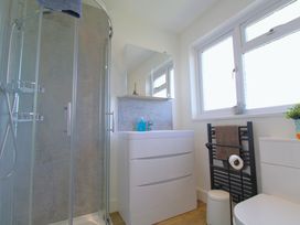 A bathroom with a shower, vanity with mirror, towel rack, and toilet at 65 Channel View in Ilfracombe