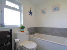 A bathroom with a bathtub toilet towel rack and window at 65 Channel View in Ilfracombe