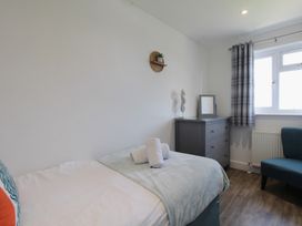 A bedroom with a bed, dresser, chair, and towels at 65 Channel View in Ilfracombe