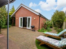 A garden with sun loungers and a grill at Birch Cottage in Brundall