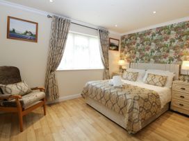 A bedroom with a bed and chair at Birch Cottage in Brundall