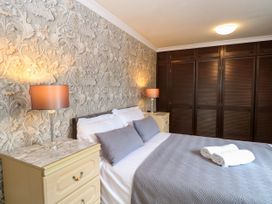 A bedroom with a bed and two bedside tables at Birch Cottage in Brundall