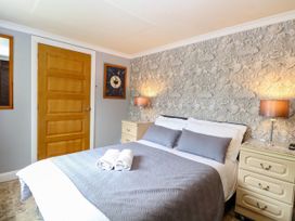 A bedroom with a bed and nightstand at Birch Cottage in Brundall