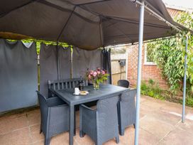 An outdoor patio with a table and chairs at Birch Cottage in Brundall