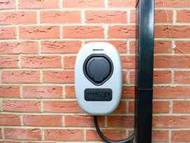 An electric vehicle charging station mounted on a brick wall at Birch Cottage in Brundall