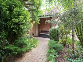 A garden with a pathway and a bench at Birch Cottage in Brundall