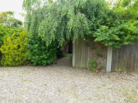A garden with a pathway leading to a doorway at Birch Cottage in Brundall