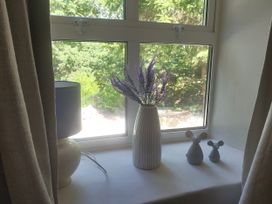 A windowsill with a lamp, vase, flowers, and figurines at Islwyn near Bala