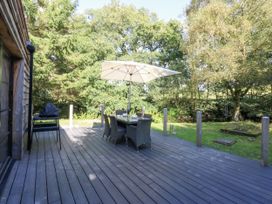 An outdoor area with a deck, table, chairs, and umbrella at Islwyn near Llanuwchllyn