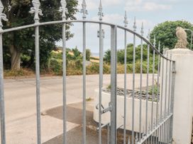 A metal gate with pointed tops beside a stone pillar and trees in a rural area at Broadsands in Paignton