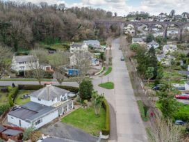 A residential street with houses trees and a large stone railway viaduct in the background at Broadsands in Paignton
