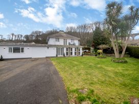 A two story white house with a driveway and lawn with trees at Broadsands in Paignton